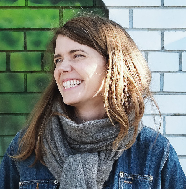 headshot of smiling woman posed in front of a mural